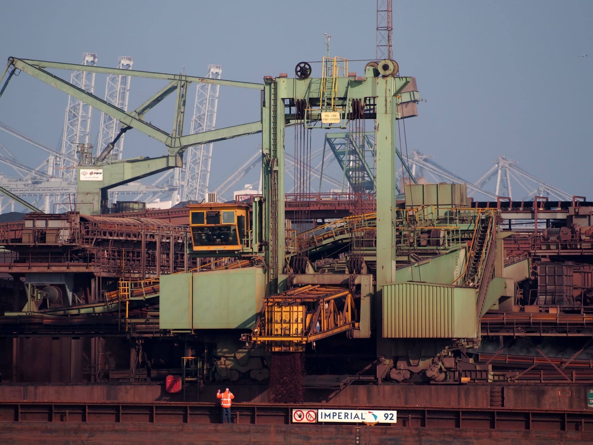 Een bulklader vult de duwbak Imperial 92 in de Hartelhaven, met een medewerker aan dek