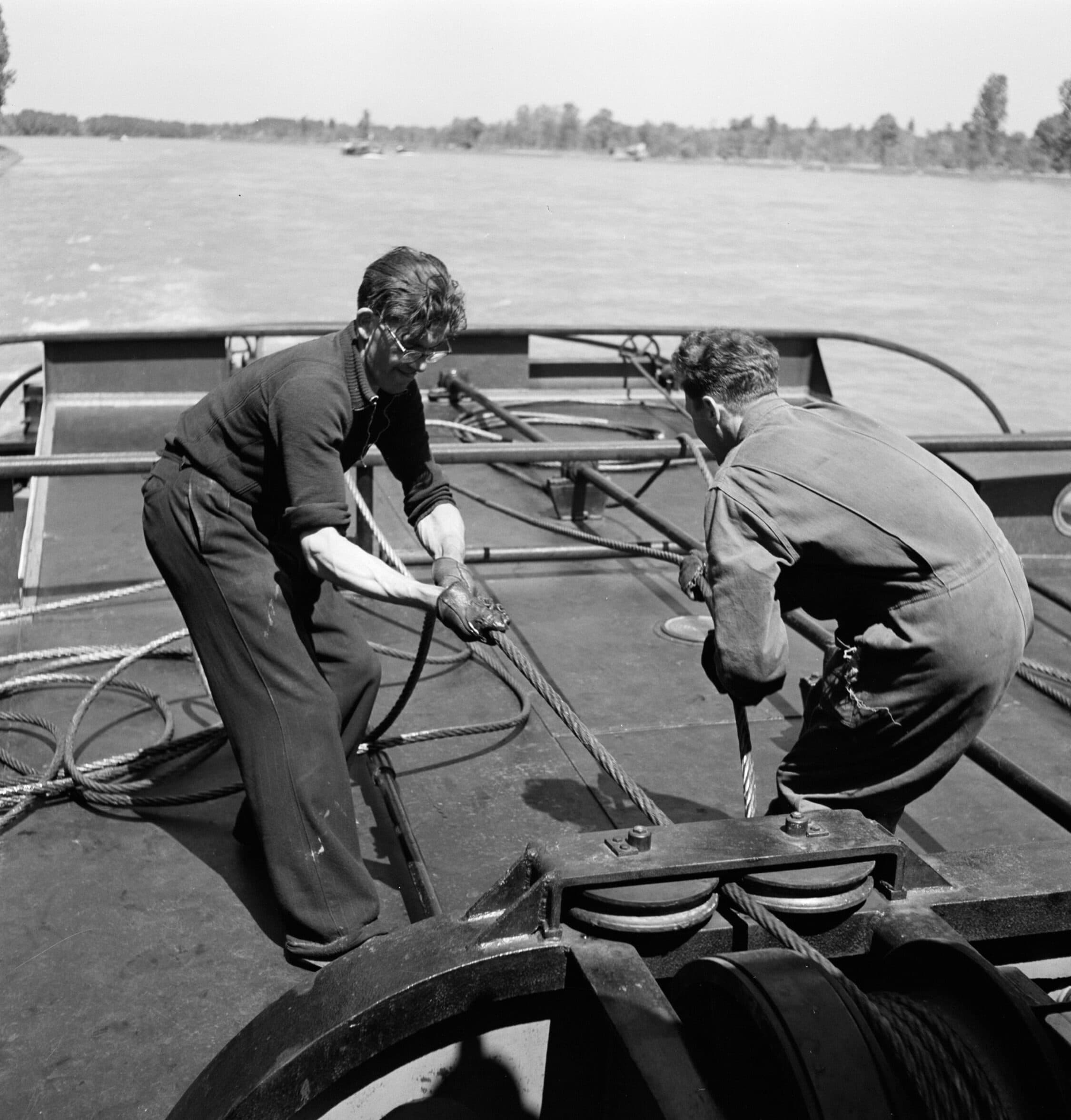 Twee bemanningsleden maken in de jaren vijftig een binnenvaartschip vast aan de Rijnsleepboot Damco 230