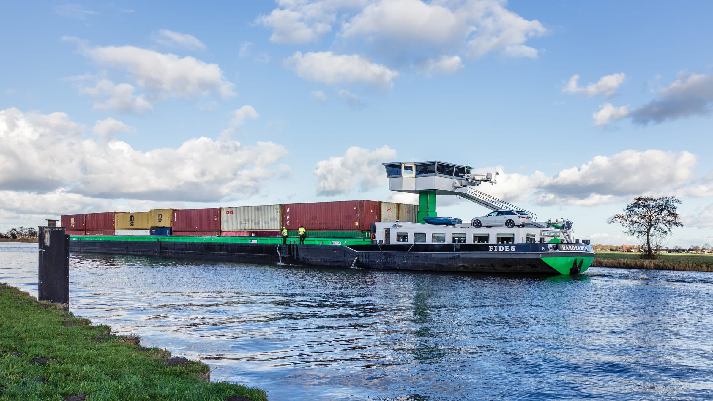 Containerbinnenvaartschip Fides onderweg, met twee bemanningsleden aan dek