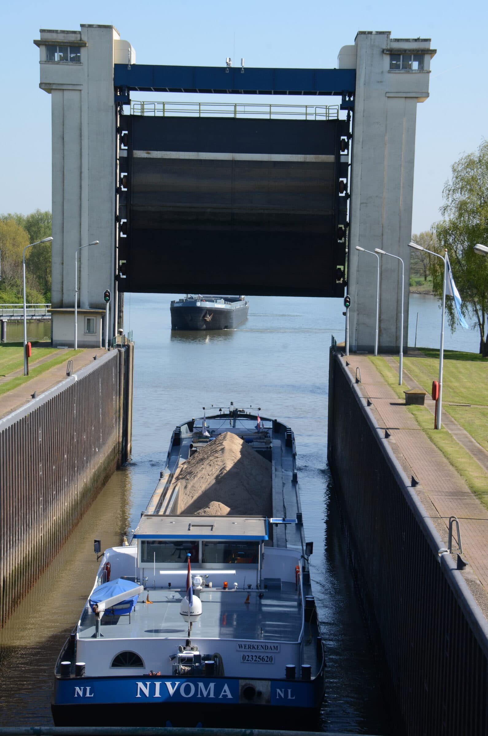Zandschip Nivoma vaart de sluis bij Dreumel uit, onder de opgehaalde hefdeur